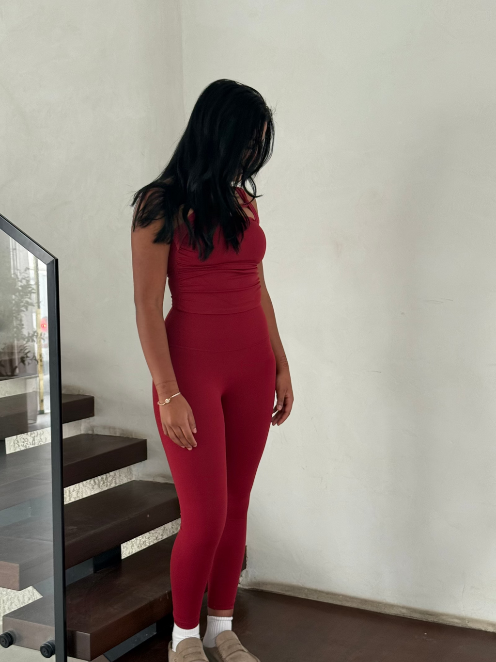 Person wearing a red outfit standing in a room with a mirror and staircase.